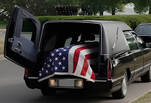 A black hearse with an american flag draped on the back.